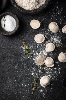 Çiğ mantı ya da siyah arka planda etli ravioli.