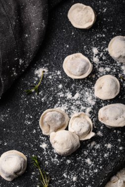 Çiğ mantı ya da siyah arka planda etli ravioli.