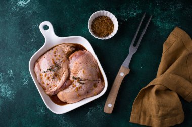 Koyu mutfak masasında çiğ tavuk butları.