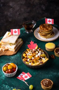 Kanada Günü geleneksel gıda konsepti. Poutine, tereyağlı tart, sandviç, akçaağaç şuruplu Kanada gözlemesi.