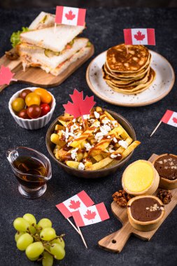 Kanada Günü geleneksel gıda konsepti. Poutine, tereyağlı tart, sandviç, akçaağaç şuruplu Kanada gözlemesi.
