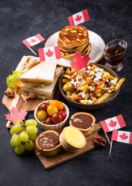 Kanada Günü geleneksel gıda konsepti. Poutine, tereyağlı tart, sandviç, akçaağaç şuruplu Kanada gözlemesi.