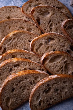 Mavi arka planda ev yapımı ekmek dilimlenmiş.