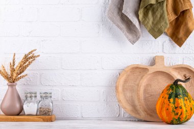 Mutfak tezgahının üstünde kavanozlar ve beyaz arka planda kesim tahtaları var.