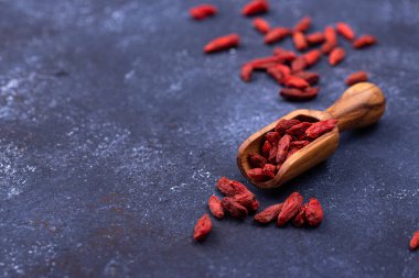 Mavi arka planda ahşap kepçe Goji üzümleri