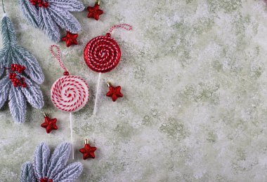 Renkli baston şeklindeki süsler, kırmızı yıldızlar ve karlı arka planda donmuş çam dalları..