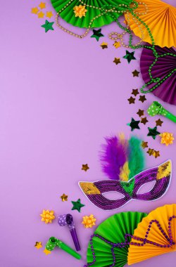 Mardi Gras arka planında mor, altın ve yeşil süslemeler, boncuklar ve karnaval maskesi var.