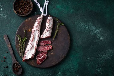 Yeşil arka planda baharatlı salam sosisi.