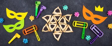 Jewish holiday Purim with carnival mask, traditional cookies Hamantaschen and rattle