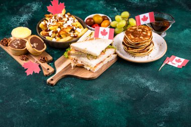 Kanada Günü geleneksel gıda konsepti. Poutine, tereyağlı tart, sandviç, akçaağaç şuruplu Kanada gözlemesi.