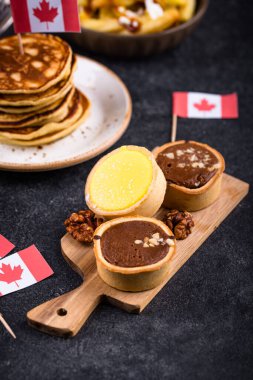 Kanada Günü geleneksel gıda konsepti. Poutine, tereyağlı tart, sandviç, akçaağaç şuruplu Kanada gözlemesi.