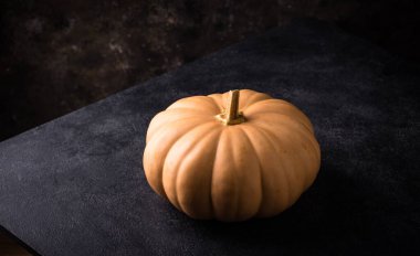 Koyu arka planda çiğ balkabağı, karanlık ruh hali tarzı.