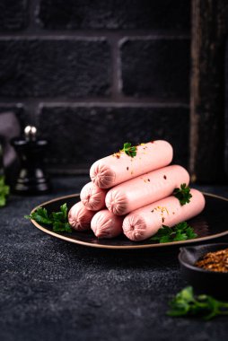 Arka planda baharatlı haşlanmış domuz sosisi.