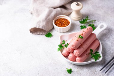 Arka planda baharatlı haşlanmış domuz sosisi.