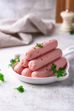 Arka planda baharatlı haşlanmış domuz sosisi.