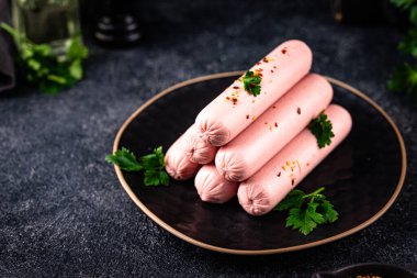 Arka planda baharatlı haşlanmış domuz sosisi.