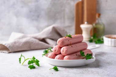 Arka planda baharatlı haşlanmış domuz sosisi.