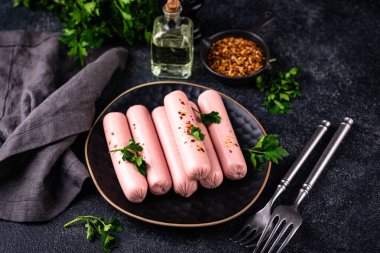 Arka planda baharatlı haşlanmış domuz sosisi.