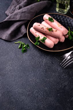 Arka planda baharatlı haşlanmış domuz sosisi.