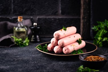 Arka planda baharatlı haşlanmış domuz sosisi.