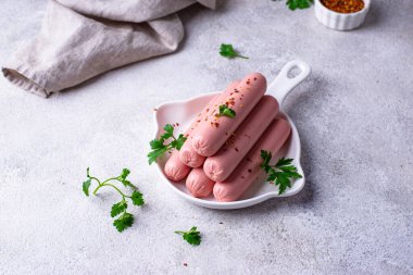 Arka planda baharatlı haşlanmış domuz sosisi.