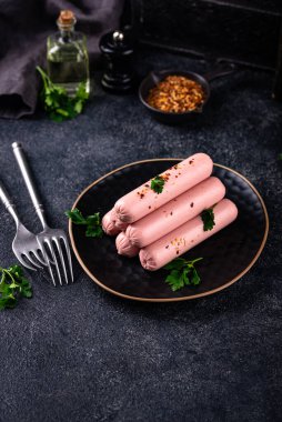 Arka planda baharatlı haşlanmış domuz sosisi.