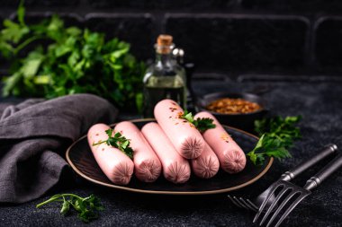 Arka planda baharatlı haşlanmış domuz sosisi.