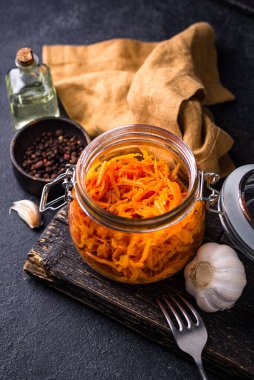 Kavanozda siyah arka planda baharatlı Kore havuç salatası