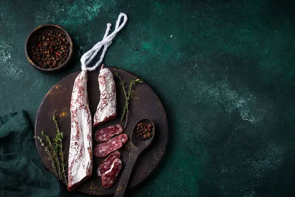 Yeşil arka planda baharatlı salam sosisi.