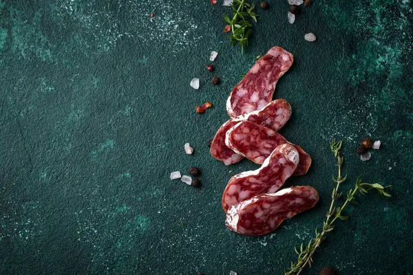 Yeşil arka planda baharatlı salam sosisi.