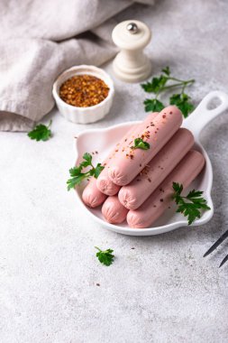 Arka planda baharatlı haşlanmış domuz sosisi.