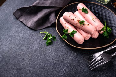 Arka planda baharatlı haşlanmış domuz sosisi.