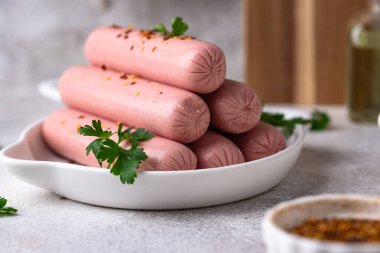 Arka planda baharatlı haşlanmış domuz sosisi.