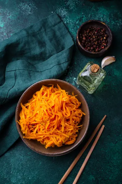 Yeşil arka planda baharatlı Kore havuç salatası.