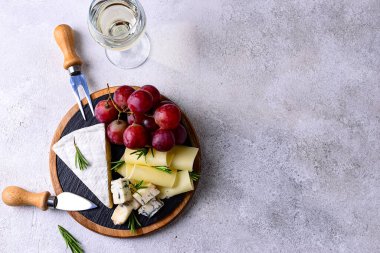 Bir bardak şarap, değişik türde yumuşak peynir ve üzümler.