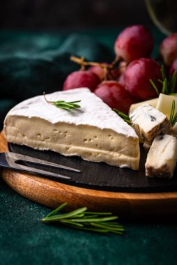 Bir bardak şarap, değişik türde yumuşak peynir ve üzümler.