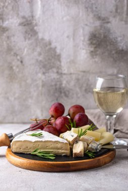 Bir bardak şarap, değişik türde yumuşak peynir ve üzümler.