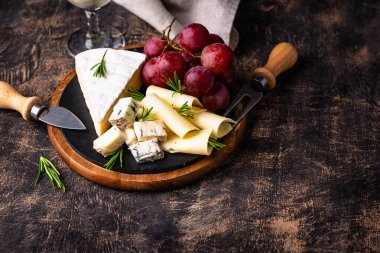 Bir bardak şarap, değişik türde yumuşak peynir ve üzümler.