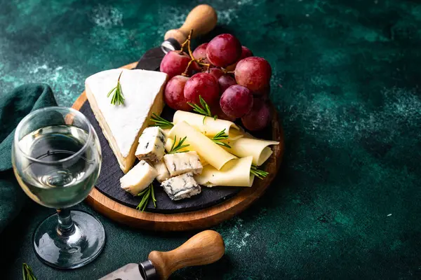 Bir bardak şarap, değişik türde yumuşak peynir ve üzümler.