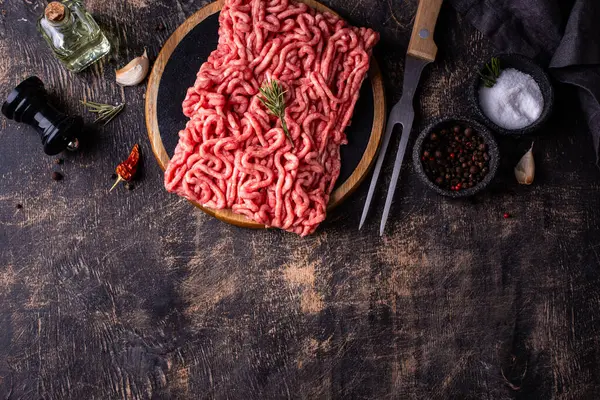 Koyu arkaplanda baharatlı çiğ et.