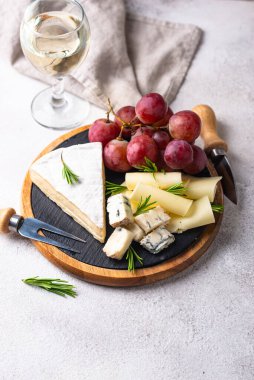 Bir bardak şarap, değişik türde yumuşak peynir ve üzümler.