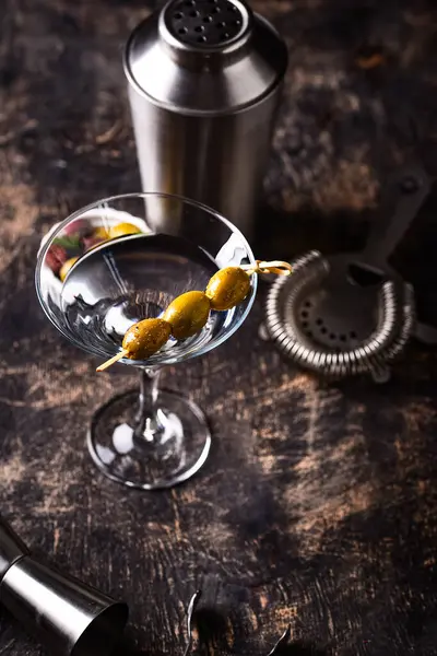 Zeytin ve barmen aletli geleneksel martini kokteyli.