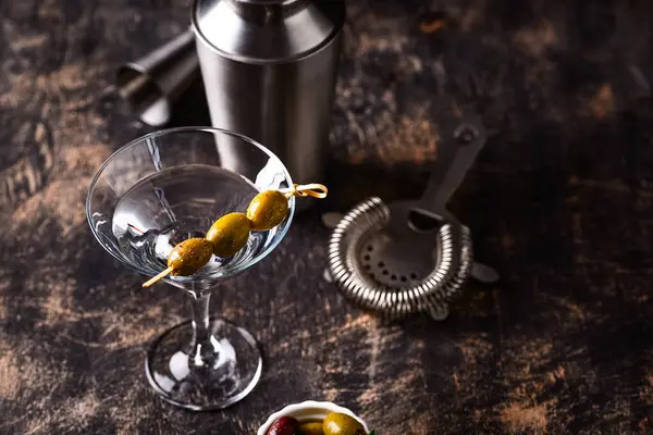 Zeytin ve barmen aletli geleneksel martini kokteyli.
