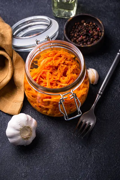 Kavanozda siyah arka planda baharatlı Kore havuç salatası