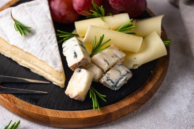 Bir bardak şarap, değişik türde yumuşak peynir ve üzümler.