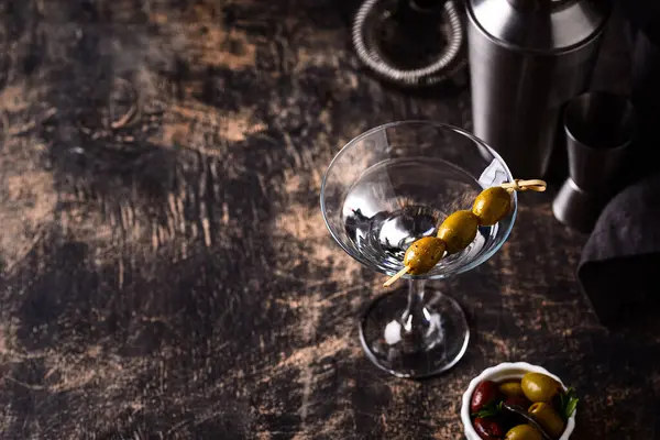 Zeytin ve barmen aletli geleneksel martini kokteyli.