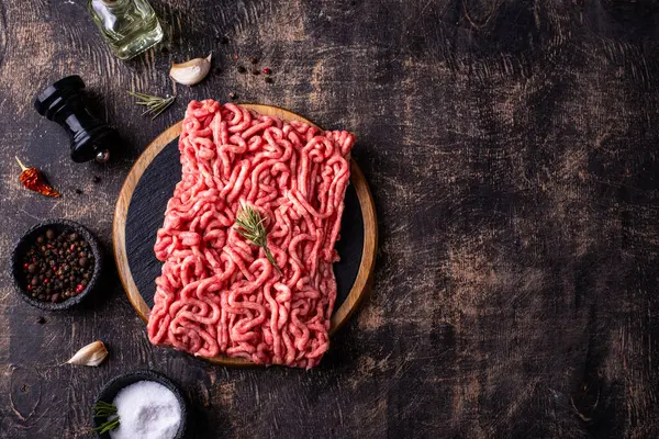 Koyu arkaplanda baharatlı çiğ et.