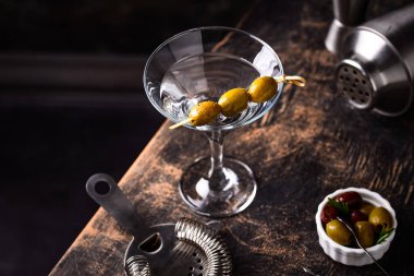 Zeytin ve barmen aletli geleneksel martini kokteyli.