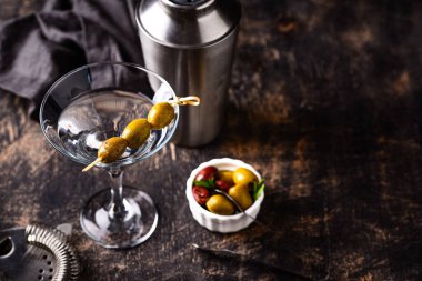 Zeytin ve barmen aletli geleneksel martini kokteyli.