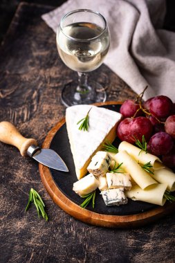 Bir bardak şarap, değişik türde yumuşak peynir ve üzümler.